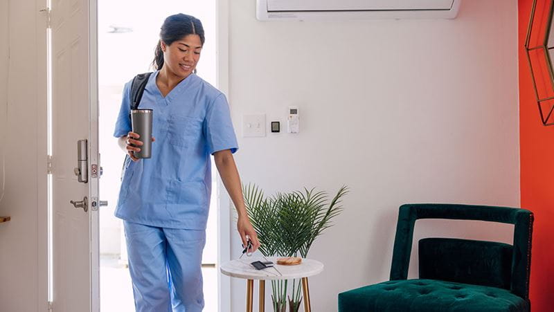 A woman in scrubs entering a house