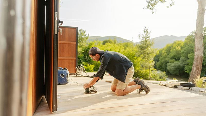 Carpenter sanding wooden deck