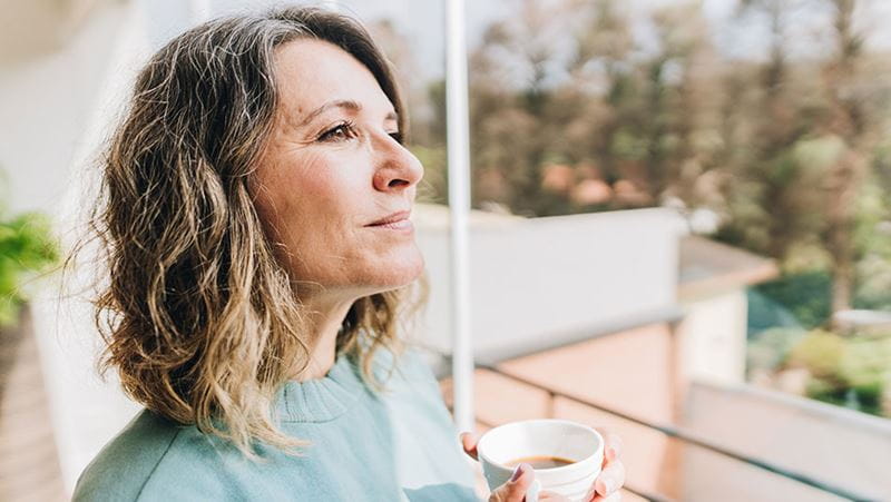 A woman with coffee looking into the distance